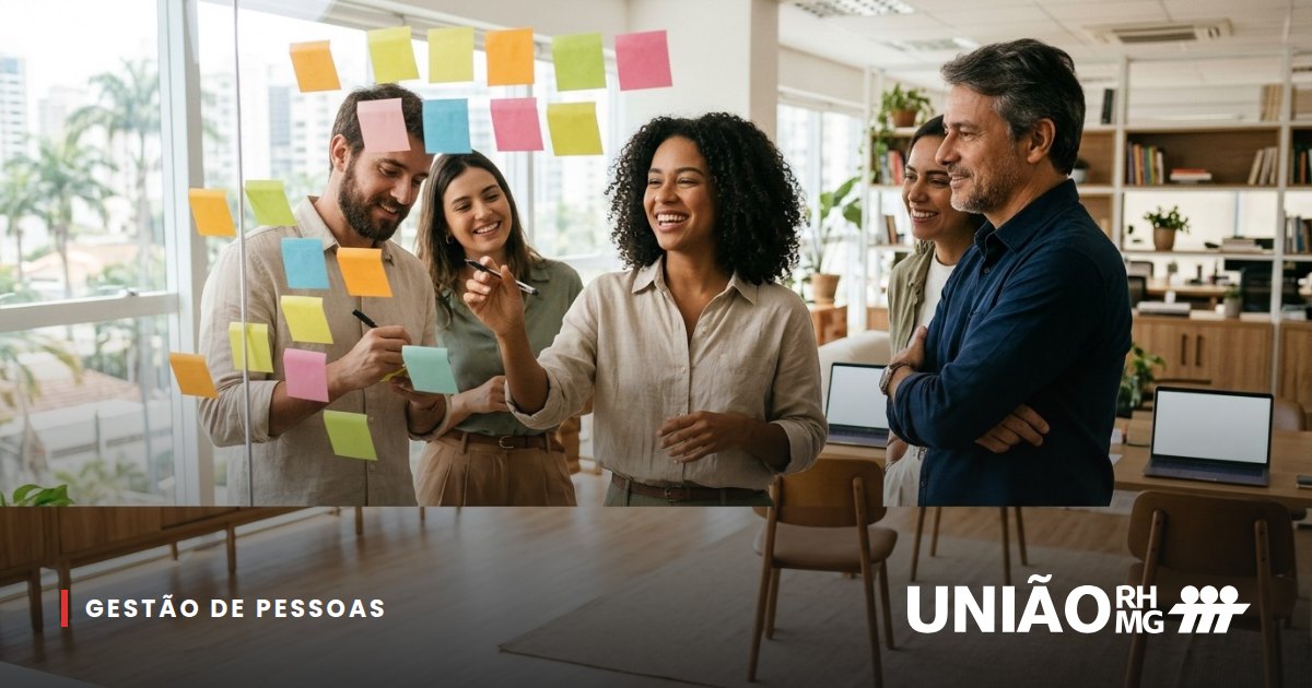 Colaboradores reunidos em frente a uma parede de vidro com post-its, trocando ideias com a gestora